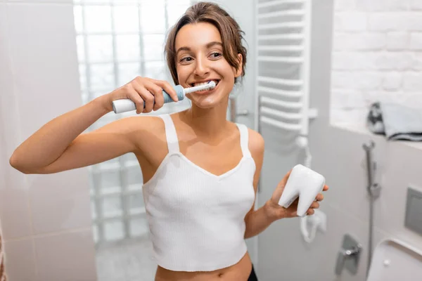 Mujer limpiando dientes con cepillo de dientes eléctrico —  Fotos de Stock