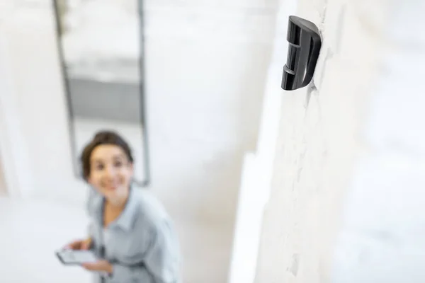 Mujer que controla el sistema de alarma con un teléfono inteligente — Foto de Stock