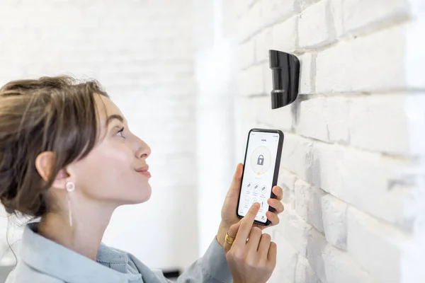Женщина управляет системой сигнализации со смартфоном — стоковое фото