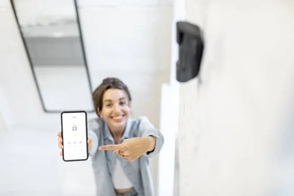 Alarm sistemini akıllı bir telefonla kontrol eden kadın — Stok fotoğraf