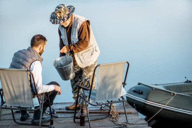 Granfother with son fishing on the lake