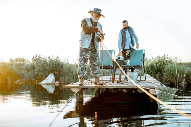 Grandfather with adult son fishing on the lake