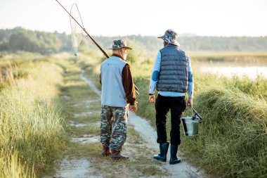 Grandfather with adult son walking near the lake