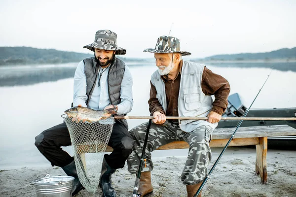 Grandfather with son fishing on the lake — 图库照片