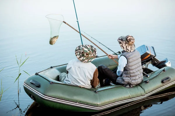 Дідусь з сином рибалить на човні — стокове фото