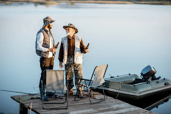 Grandfather with adult son talking on fishing — Stock fotografie