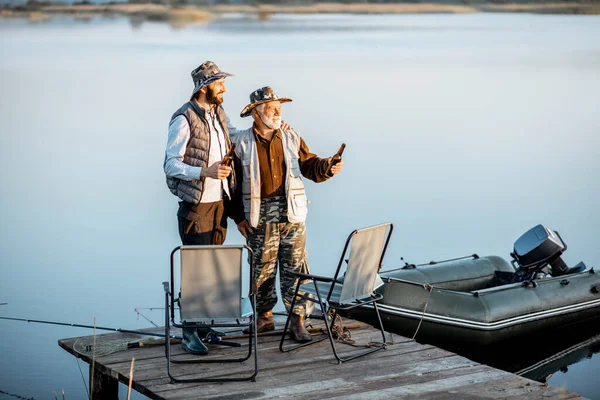 Grandfather with adult son fishing on the lake — Stock fotografie