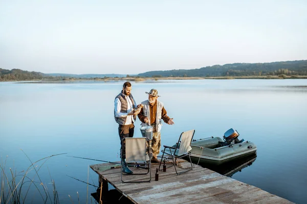 Grandfather with adult son fishing on the lake — 图库照片