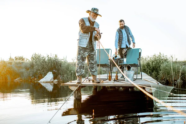 Grandfather with adult son fishing on the lake — Stock fotografie