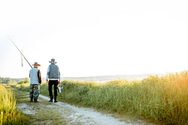 Grandfather with adult son walking near the lake — Stockfoto