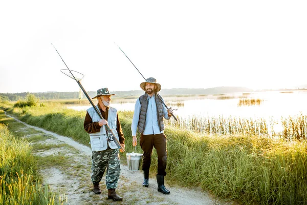 Grandfather with adult son walking near the lake — Stok fotoğraf