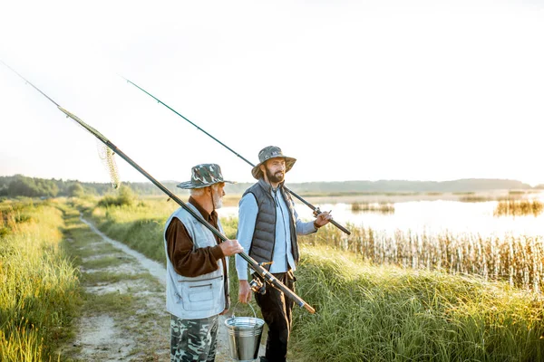 Grandfather with adult son walking near the lake — Stockfoto