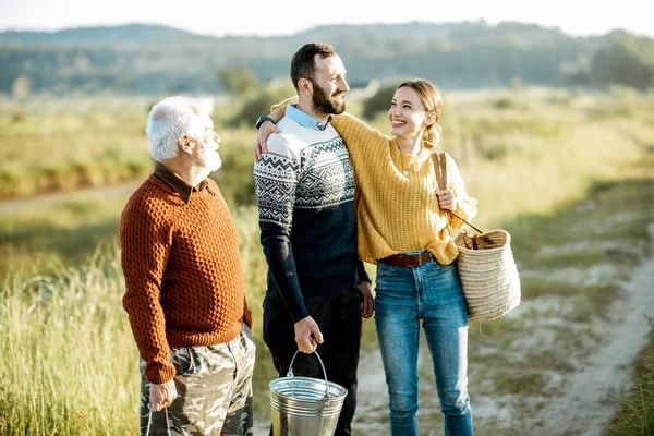 Young man and woman with senior grandfather walking outdoors — 图库照片