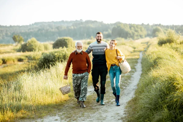 Young man and woman with senior grandfather walking outdoors — ストック写真