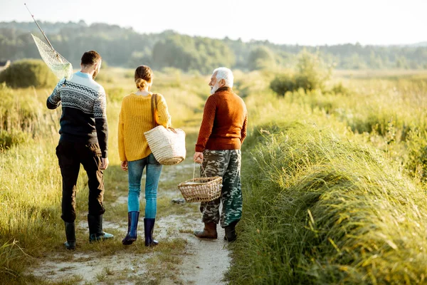 Young man and woman with senior grandfather walking outdoors — ストック写真