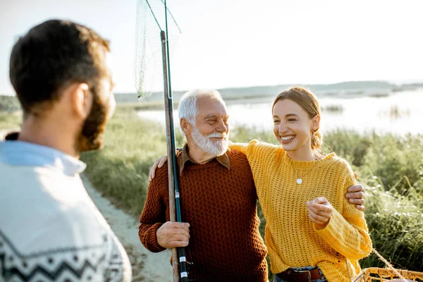 Young man and woman with senior grandfather having a good time while fishing — 图库照片