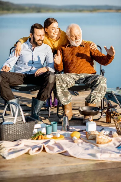 Senior grandfather talking with his adult son and daughter on the picnic — 图库照片