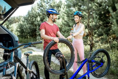 Couple with bicycles near the car in the forest