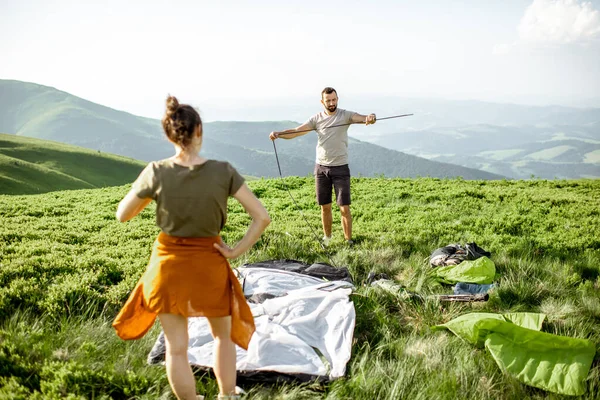 Пара, устанавливающая палатку в горах — стоковое фото