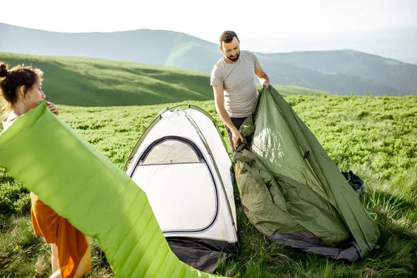 Пара, устанавливающая палатку в горах — стоковое фото