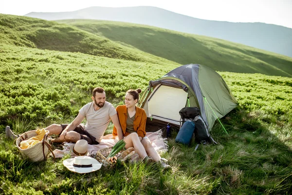 Couple having a picnic near the tent in the mountains — Stok fotoğraf