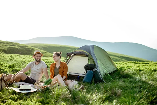 Пара устраивает пикник возле палатки в горах — стоковое фото