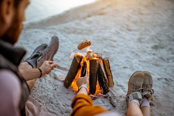 Couple cuisine saucisses sur la plage — Photo