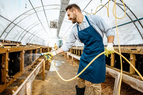 Man som arbetar på en gård med sniglar — Stockfoto