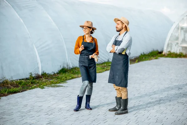 Twee boeren op een boerderij met hothouses outdooors — Stockfoto