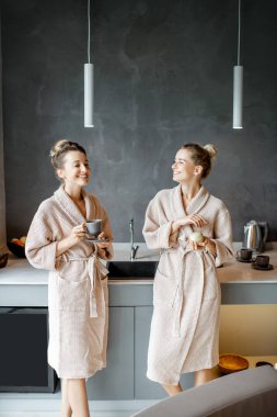 Bornozlu kadınlar mutfakta dinleniyor.