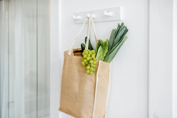 Shopping bag full of fresh vegetables hanging indoors — Stock Photo, Image