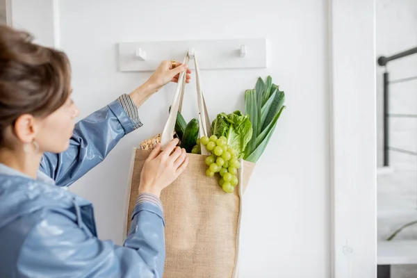 Mulher chegando em casa com saco de compras cheio de comida fresca — Fotografia de Stock