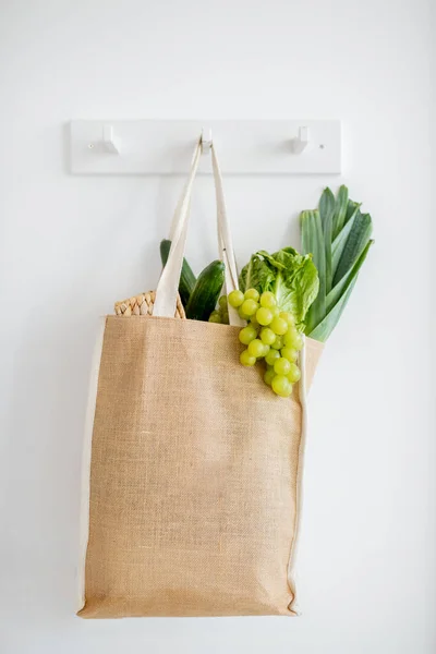 Saco de compras cheio de legumes frescos pendurados dentro de casa — Fotografia de Stock