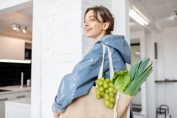 Γυναίκα έρχεται στο σπίτι με τσάντα ψώνια γεμάτη φρέσκα τρόφιμα — Φωτογραφία Αρχείου
