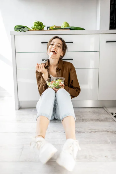 Mulher com comida saudável no chão da cozinha — Fotografia de Stock