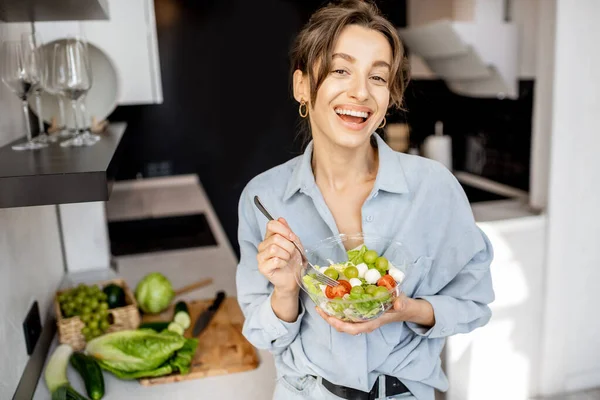 Kvinna med hälsosam sallad på köket — Stockfoto