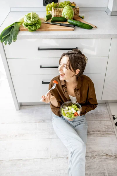 Mulher com comida saudável no chão da cozinha — Fotografia de Stock