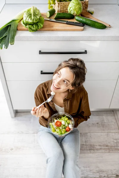 Mulher com comida saudável no chão da cozinha — Fotografia de Stock