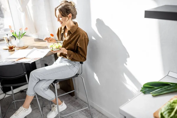 Mutfakta salata yiyen kadın. — Stok fotoğraf