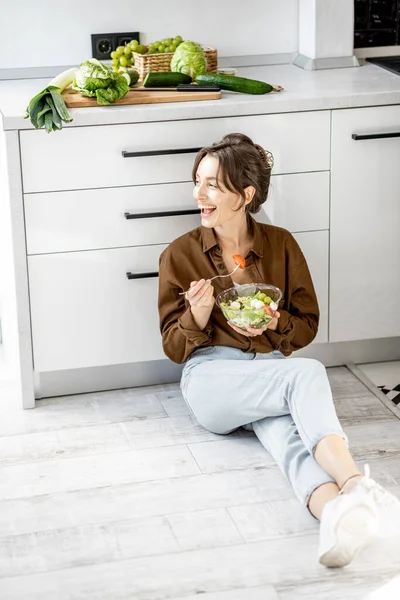Mulher com comida saudável no chão da cozinha — Fotografia de Stock