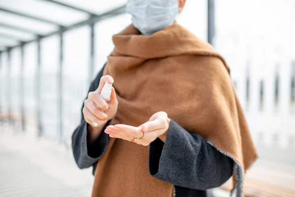 Жінка обприскує антисептик на руках на відкритому повітрі — стокове фото