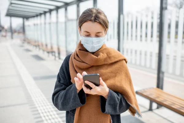 Жінка з маскою обличчя і смартфоном під час епідемії на відкритому повітрі — стокове фото