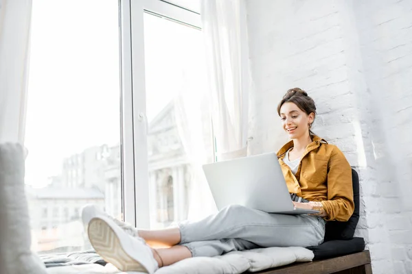 Woman with laptop on the window sill — Stock Photo, Image