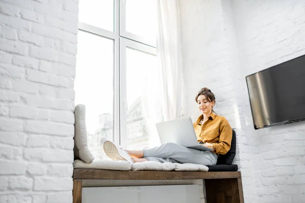 Kvinna med bärbar dator på fönsterbrädan — Stockfoto