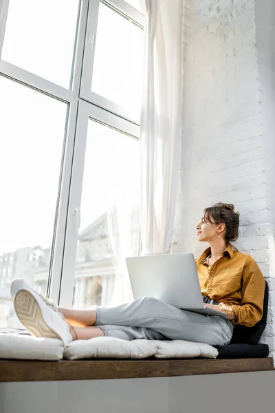 Femme avec ordinateur portable sur le rebord de la fenêtre — Photo