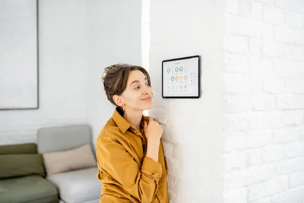 Frau steuert Haus mit digitalem Touchscreen — Stockfoto