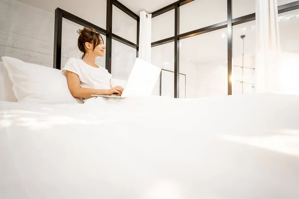 Vrouw met laptop op glanzende slaapkamer — Stockfoto