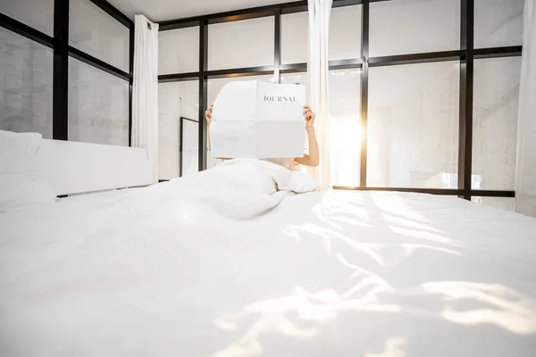 Vrouw met tijdschrift in zonnige slaapkamer — Stockfoto