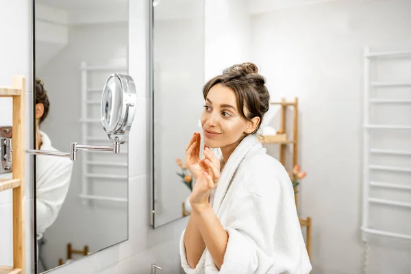 Frau schaut im Badezimmer auf ihre Haut — Stockfoto