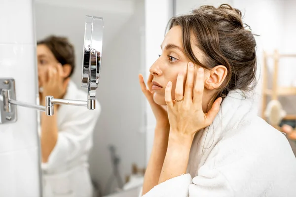 Mujer mirando en su piel en el baño — Foto de Stock